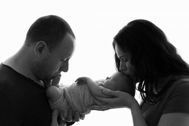 New parents kissing newborn baby girl