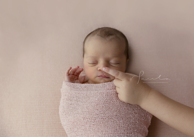 big sister touching newborn nose