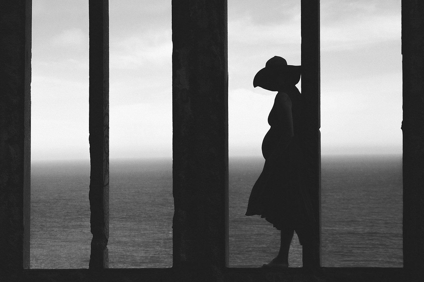 Silhouette of pregnant lady in beachfront window