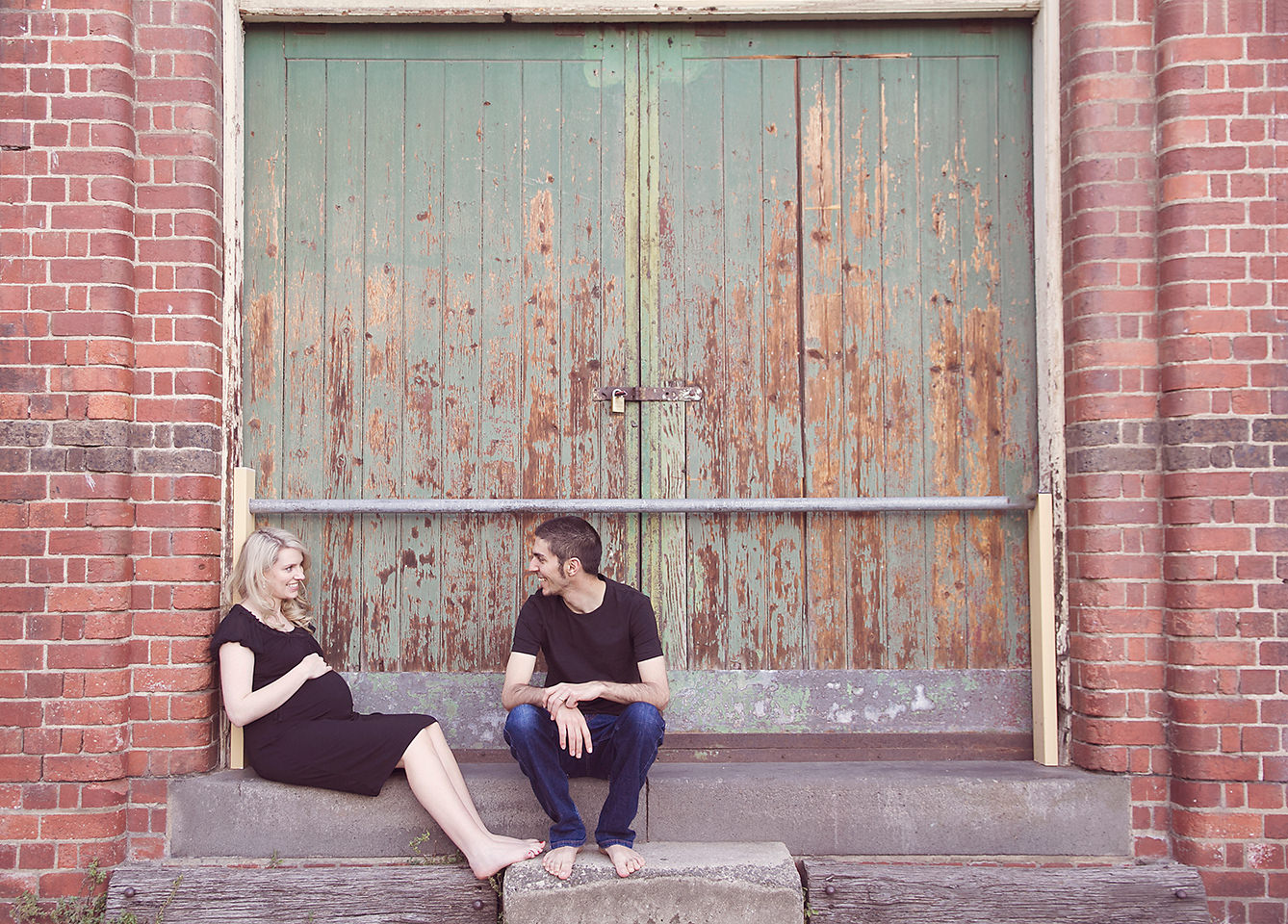 Pregnant wife and husband relax in green doorway