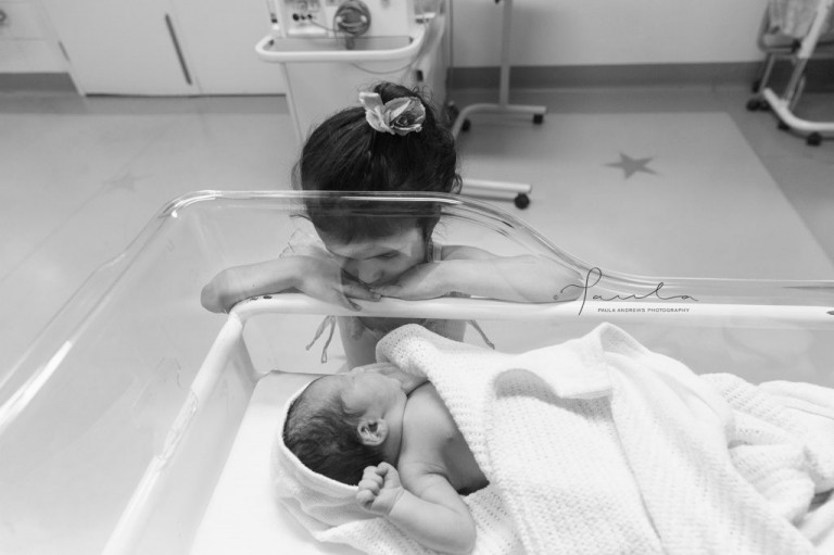 Older sister gazing at newborn baby brother