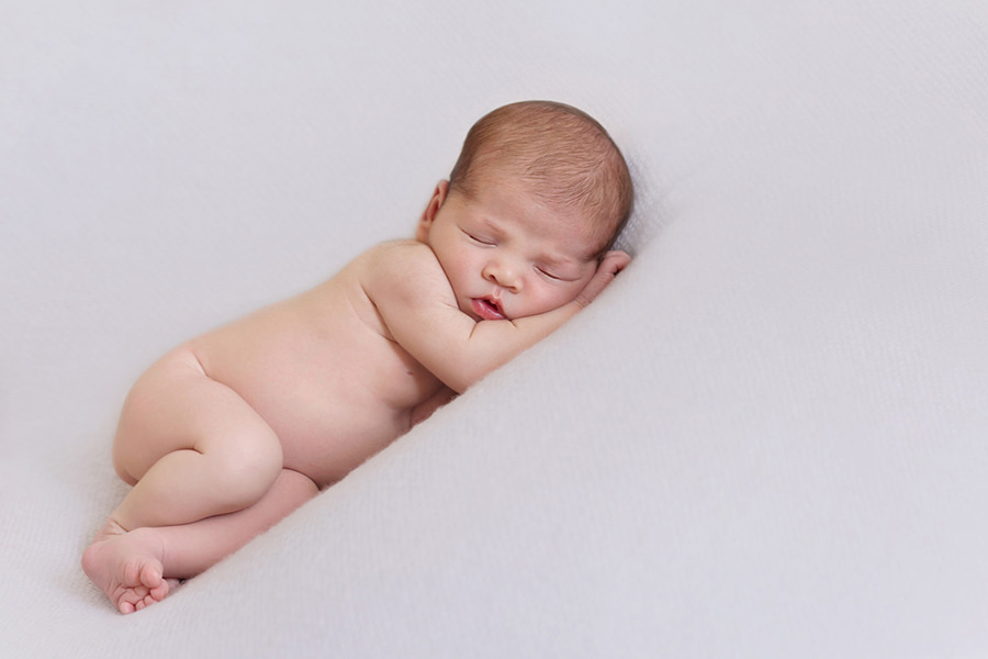 Dark haired baby sleeping on his side