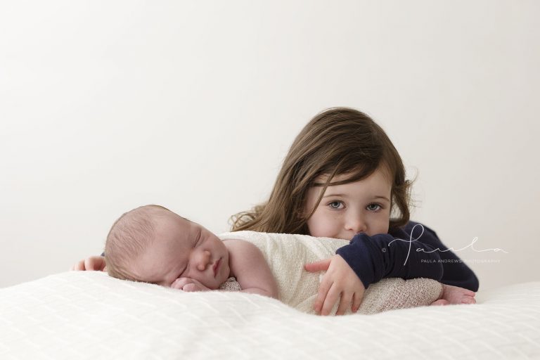 Newborn being cuddled by big sister