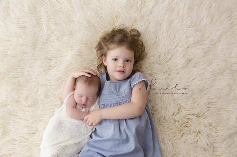 Sister hugging newborn sister