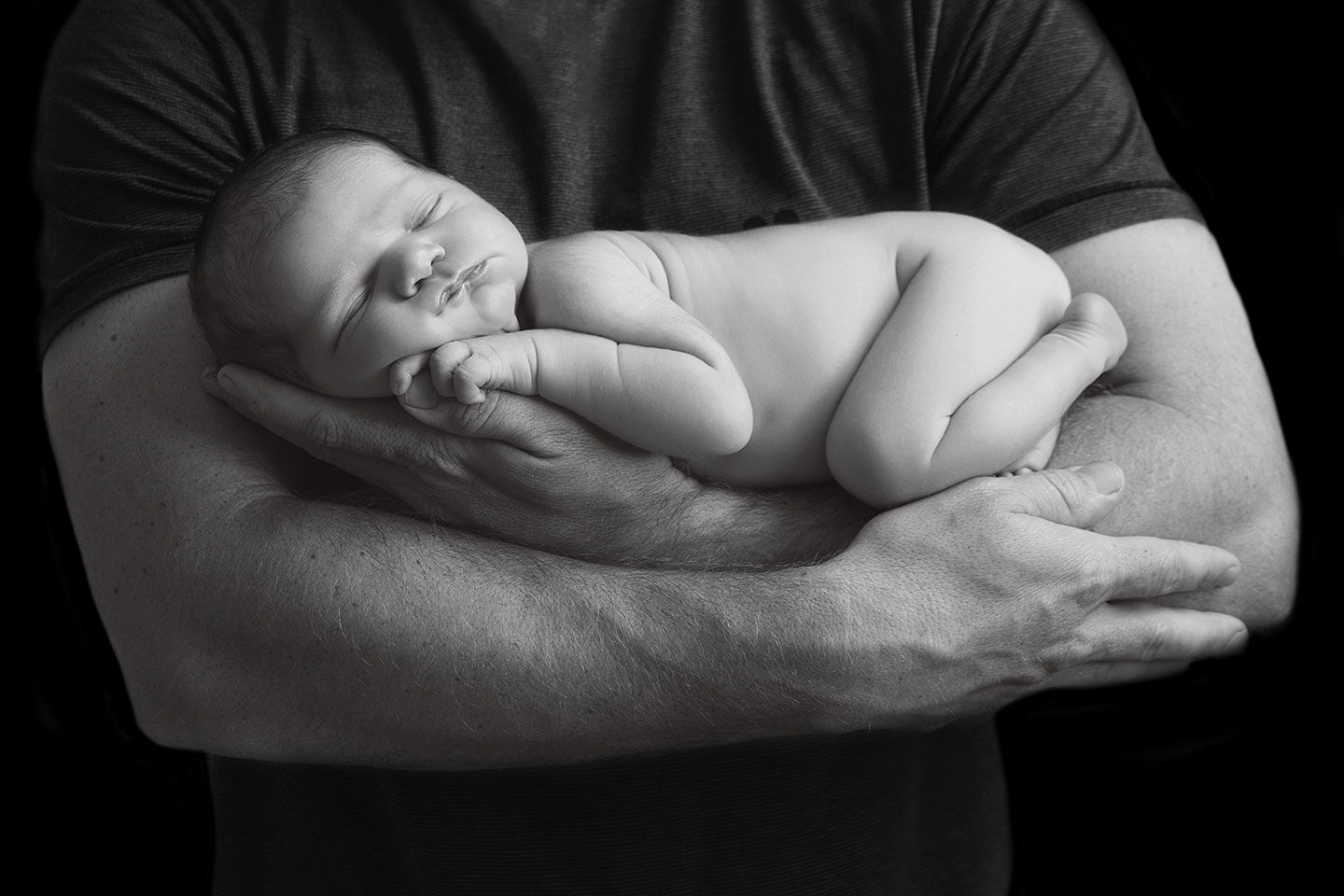 Father cradling newborn son in his arms