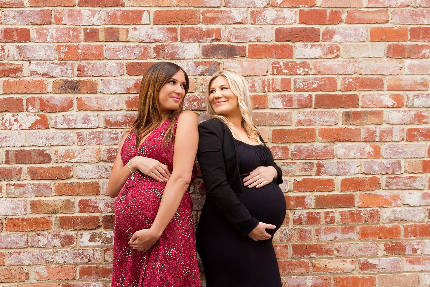 Pregnant best friends urban maternity shoot in front of brick wall