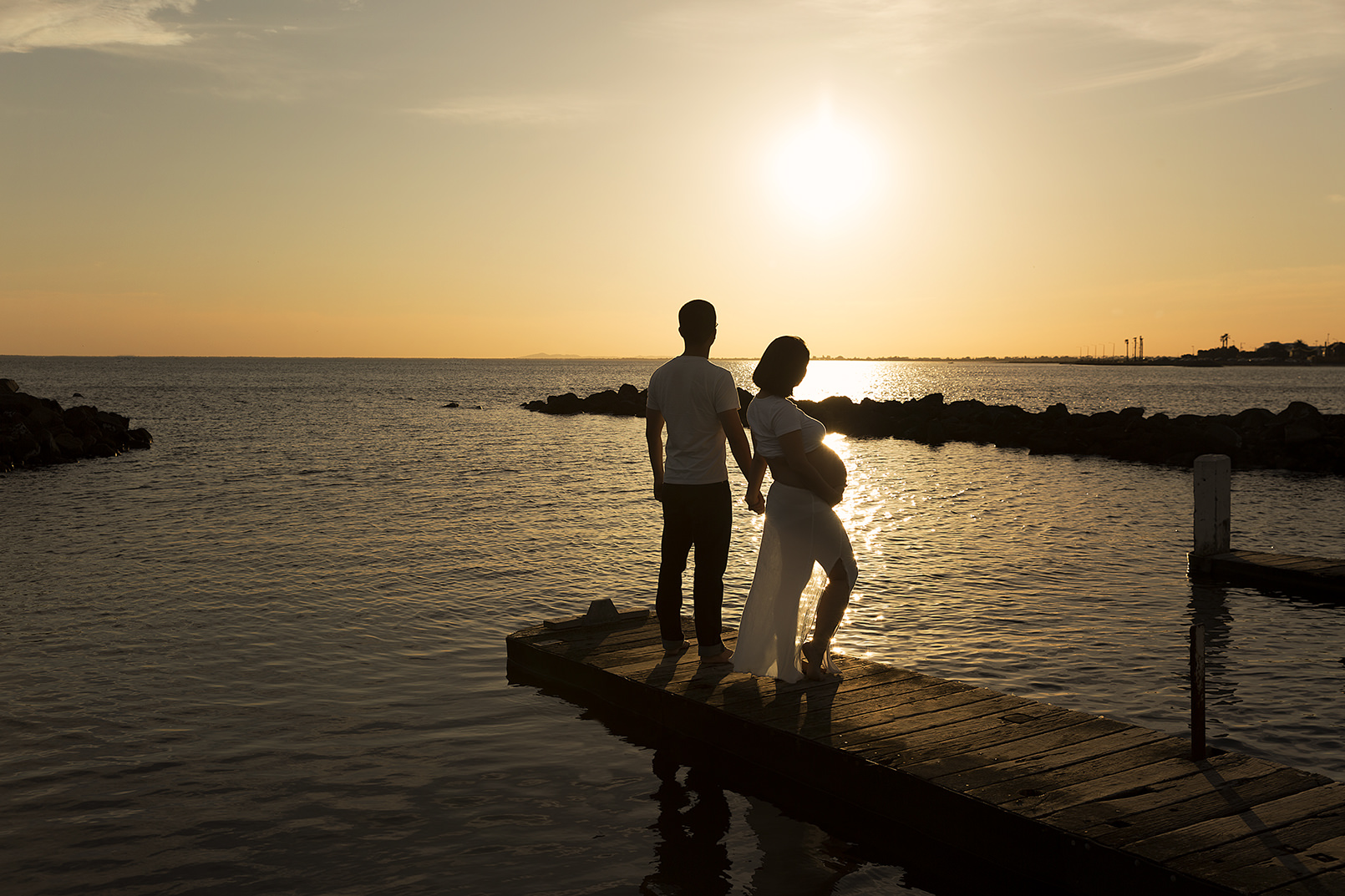 Pregnant couple watch the sunset at Williamstown Beach