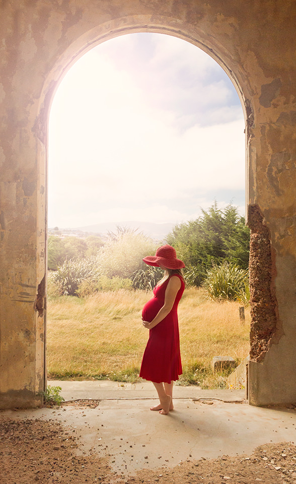 Pregnant lady in red dress in castle archway