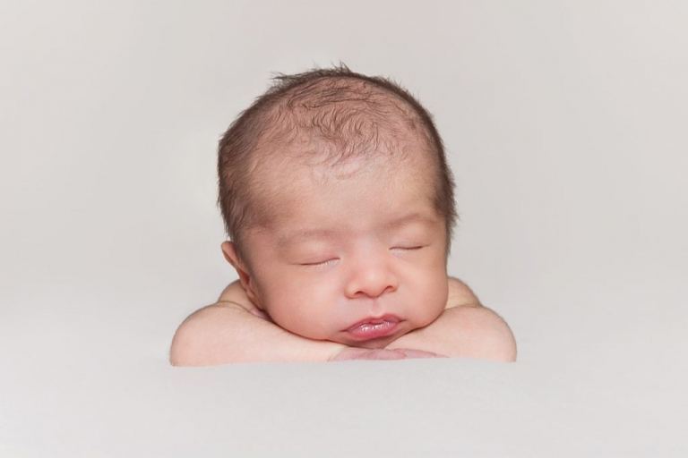 Newborn with chin on arms