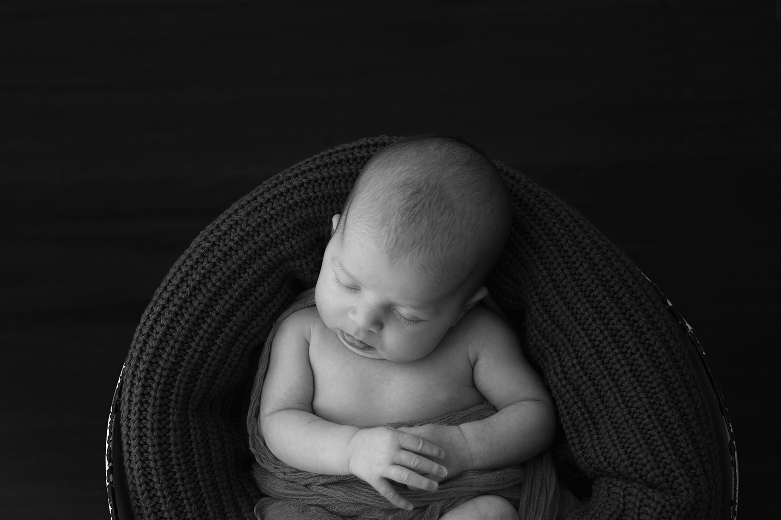 Content newborn nestled in dark blanket