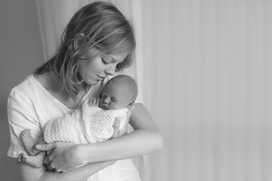 mother cuddling newborn daughter