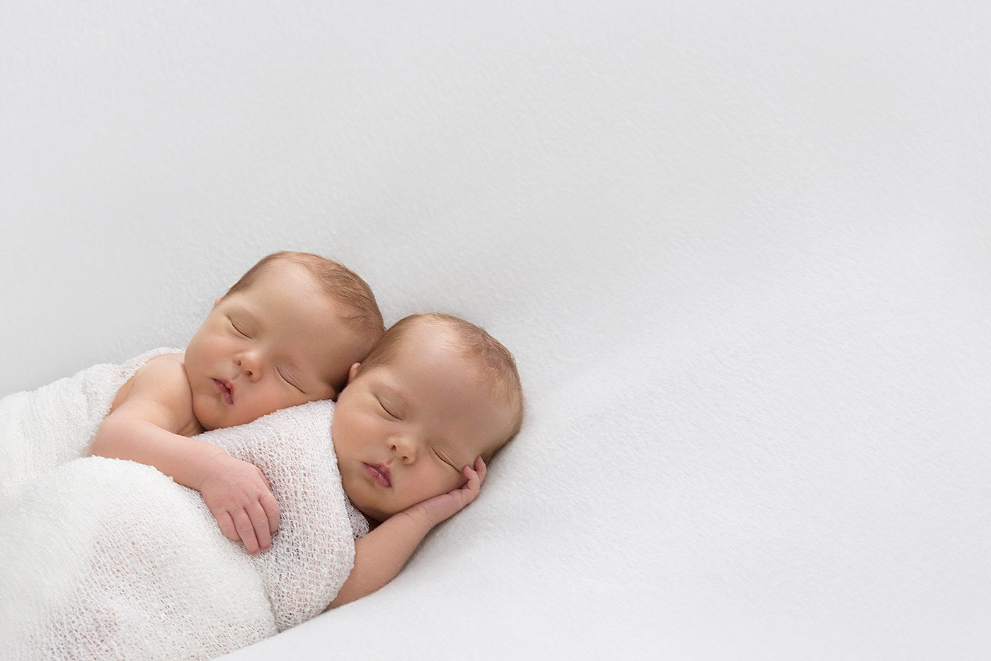 Newborn twin hugs her baby sister