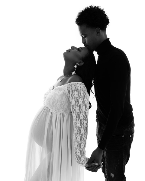 Yung African father kissing his pregnant African wife on forehead during maternity photoshoot