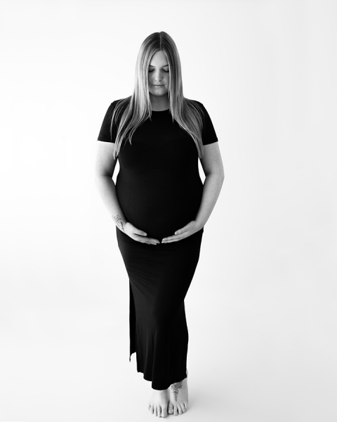 Blonde haired pregnant woman in black dress at maternity photoshoot