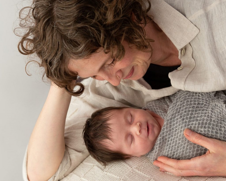 new mother looking lovinly at her smiling newborn baby in her arms
