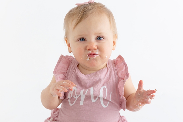 one year old baby girl eating cake at cake smash photoshoot in Melbourne